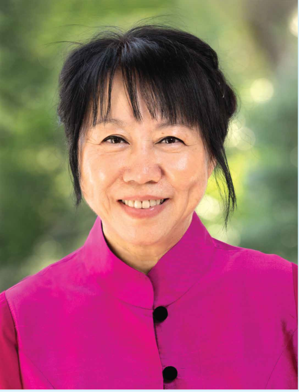 A smiling image of Ms Jane Ittogi with fushia blouse with mandarin collar and two black buttons